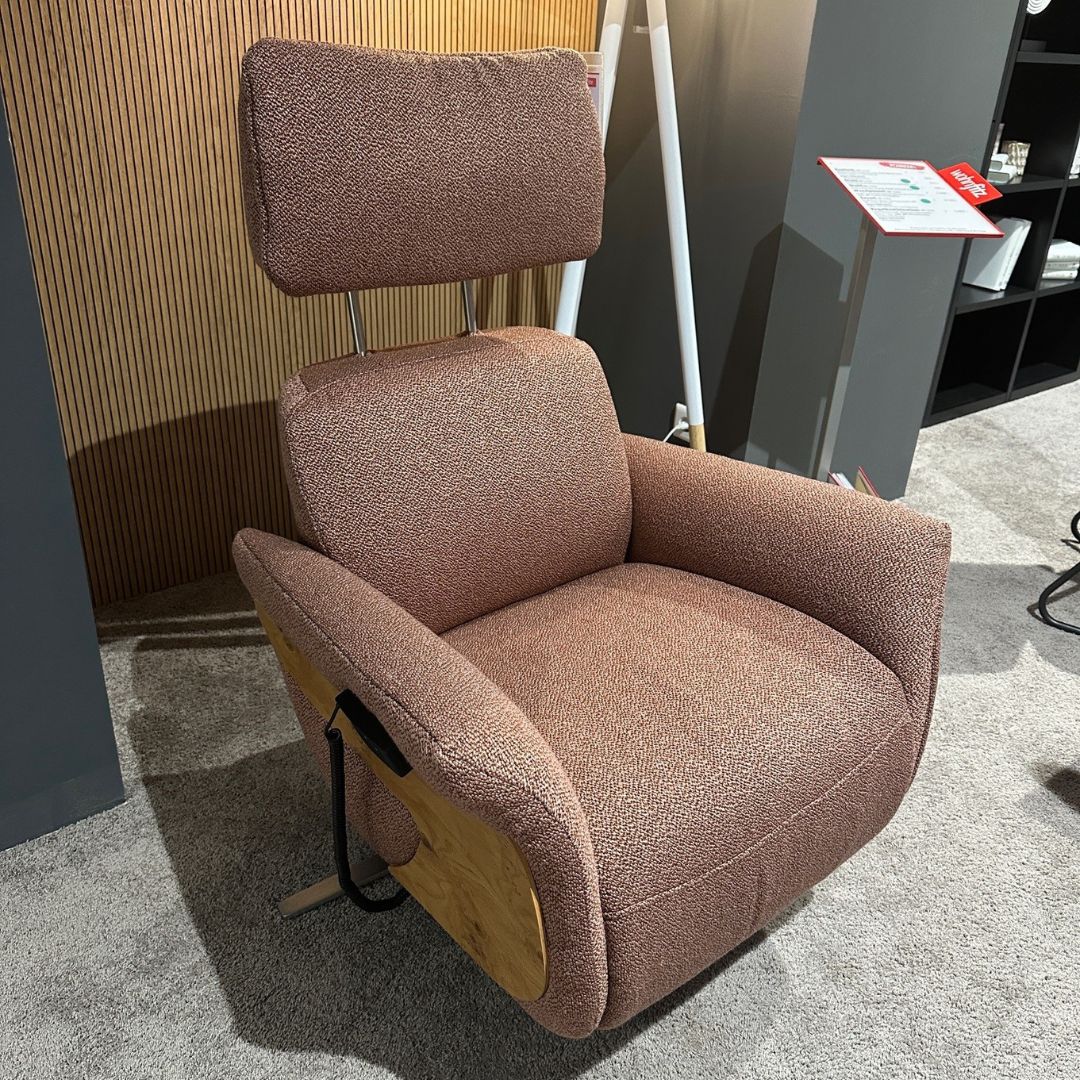 Ein komfortabler, brauner Sessel mit verstellbarer Kopfstütze und Holzdetails, ausgestellt in einem Showroom.