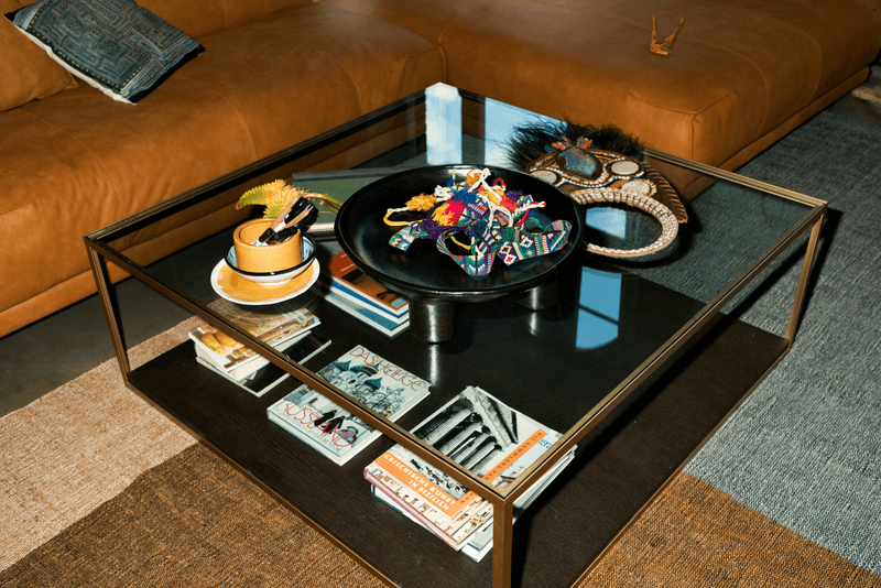 Glas-Couchtisch mit kreativem Aufbau; Dekorative Gegenstände und Bücher auf und unter dem Tisch