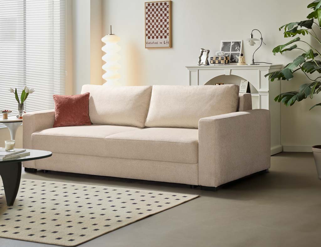 Restyl Lindsey - Schlafsofa (Querschläfer) | beige | mit Bettkasten | 165 x 200 cm Modernes Wohnzimmer mit beigem Sofa, rotem Kissen, Stehlampe und Pflanzen