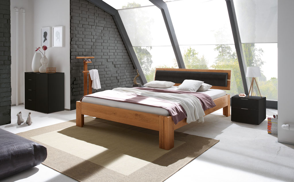 modernes Bett in braun mit Holzkopfteil und Polsterkissen am Kopfteil stilvoll dekoriert in einem modernen Zimmer