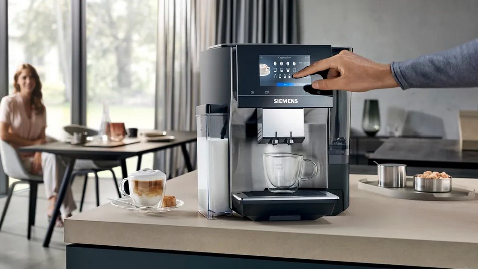 Person verwendet eine Siemens Kaffeemaschine mit integriertem Touchscreen in einer modernen Küche, Kaffeezubereitung im Gange.