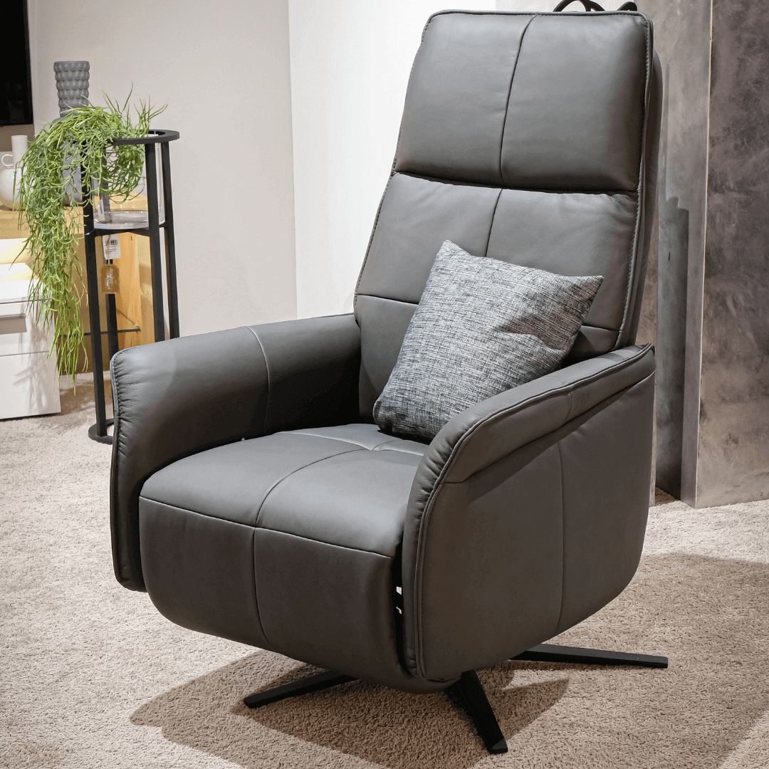 Himolla Joker 9361 | Relaxsessel | Leder Soft-Nappa, Bezug Nero Ein moderner, grauer Relaxsessel mit einem grauen Kissen steht auf einem Teppich in einem stilvoll eingerichteten Wohnzimmer.