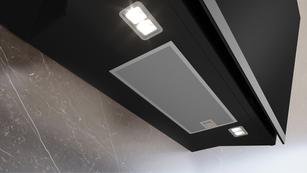 Nahaufnahme einer modernen Dunstabzugshaube mit integrierter LED-Beleuchtung und Edelstahlfilter in einer Küche