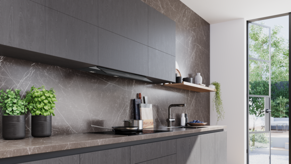 Weitwinkelaufnahme der Dunstabzugshaube im Betrieb über einem Kochfeld in einer minimalistisch gestalteten Küche mit Marmorrückwand.