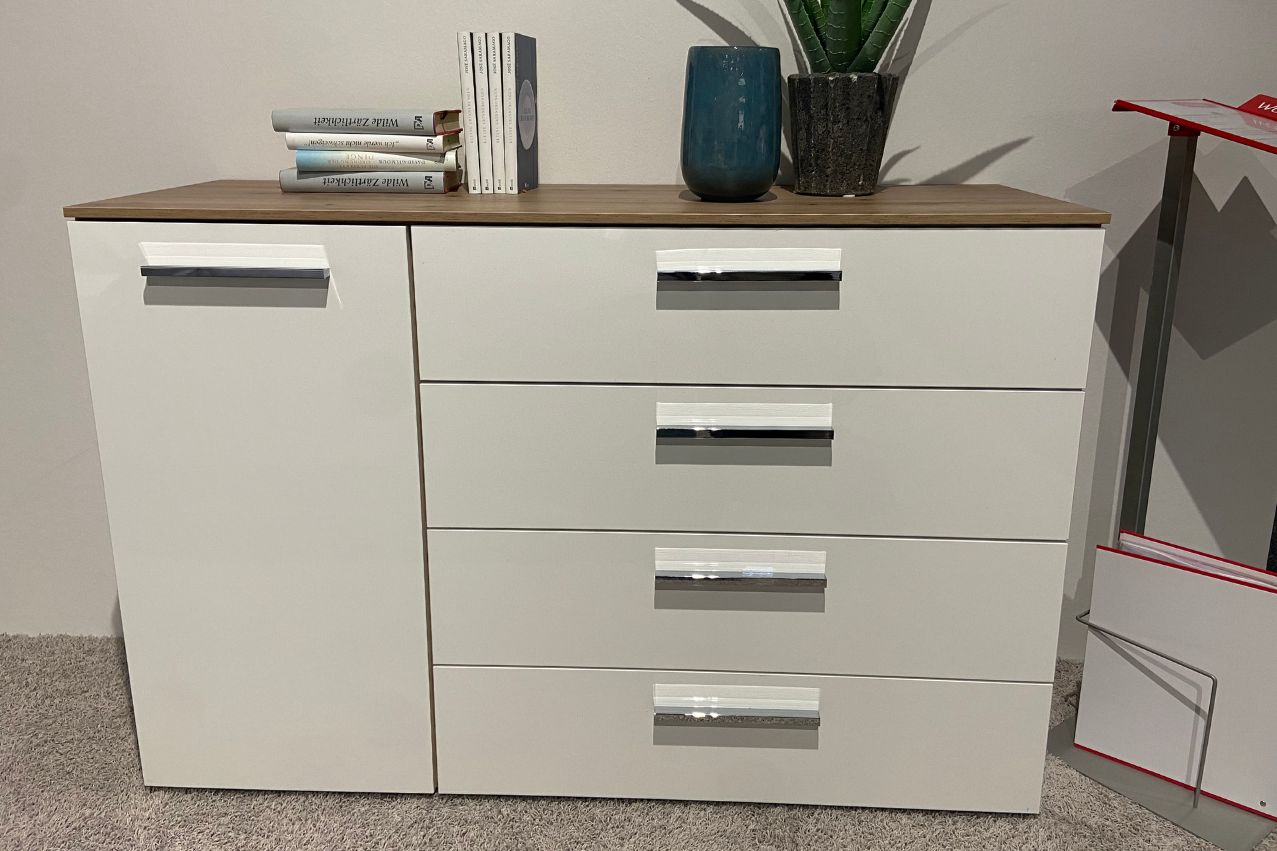 Rauch - Aldono | Kommode Eiche artisan Weißer Schrank mit vier Schubladen und einer Tür, dekoriert mit Büchern und einer Pflanze auf der Holzplatte