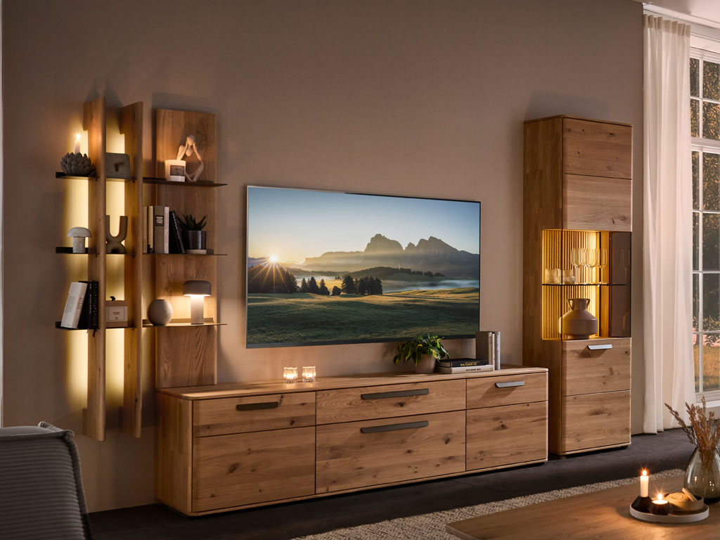 moderne Wohnwand aus Eiche mit einem großen Lowboard, beleuchtetem Regal und beleuchteter Vitrine stilvoll dekoriert in einem modernem Zimmer