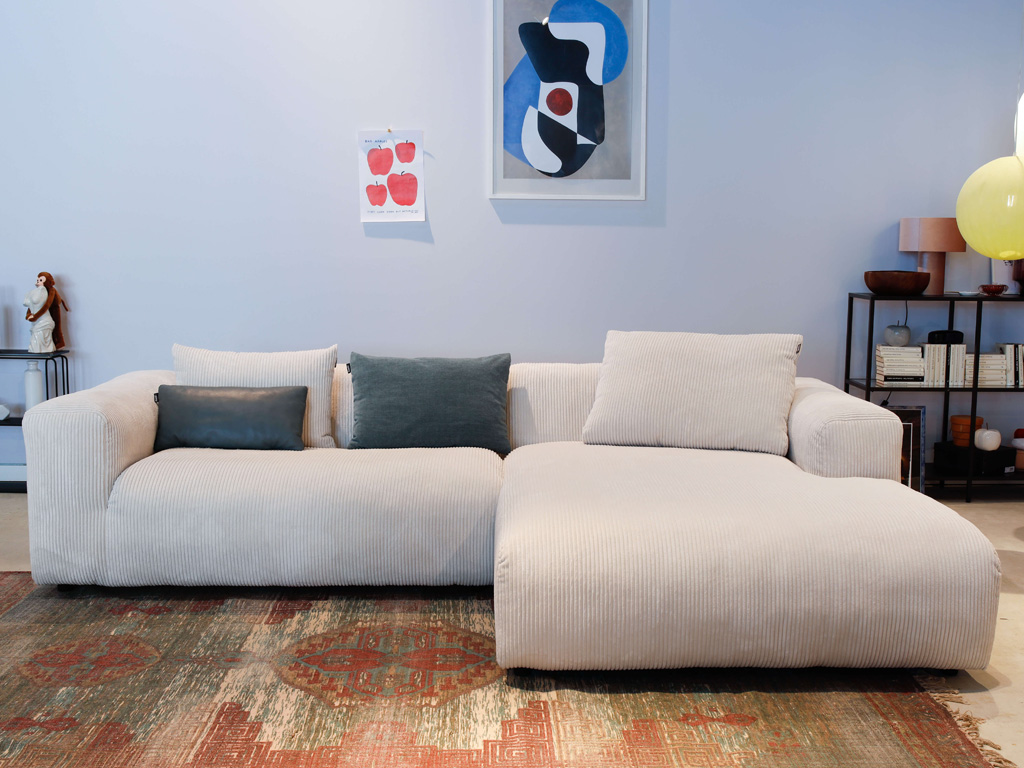 freistil Rolf Benz 187 - Polstergarnitur | Cord Sonderedition | B: 280 cm Ein modernes, beiges Ecksofa in einem geschmackvoll eingerichteten Wohnzimmer mit Wandkunst und Dekorationen.