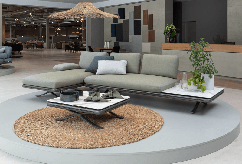 Elegante Lounge-Ecke mit modernem Sofa und Tisch auf rundem Teppich in einem stilvollen Showroom-Ambiente