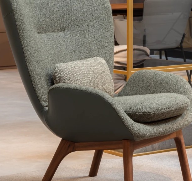 Detailaufnahme eines grünen Polstersessel mit markanten Armlehnen und Rückenkissen