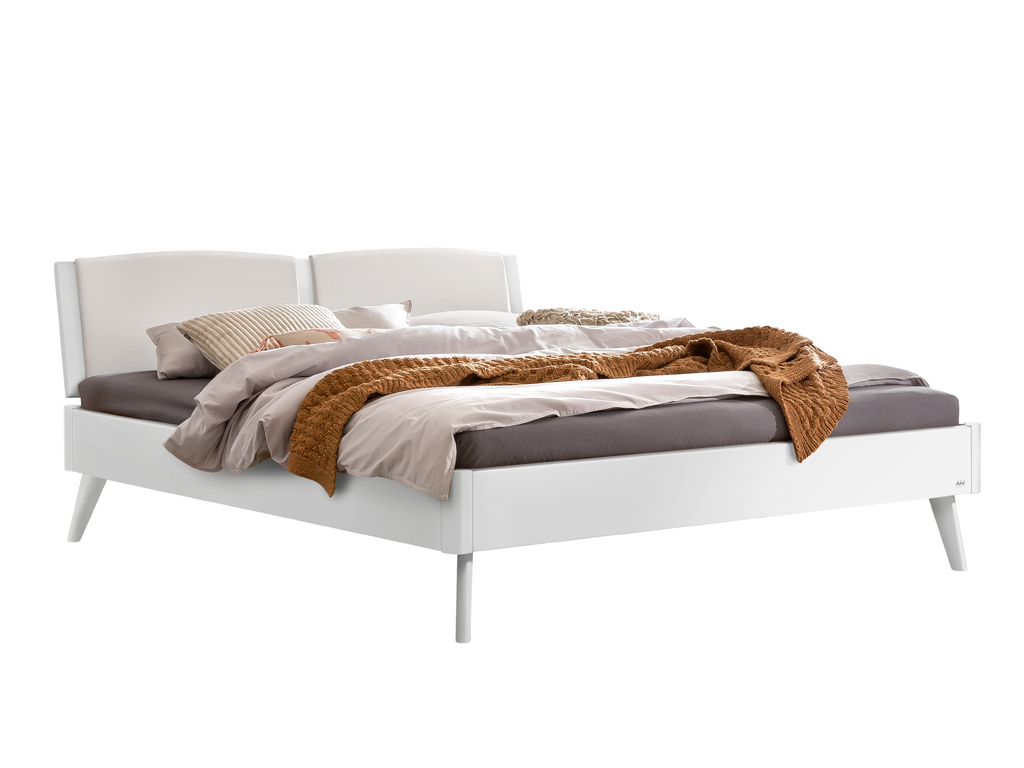 Ein modernes, komplett weiß lackiertes Doppelbett mit einem geteilten, weißen, gepolsterten Kopfteil. Es ist mit einer braunen Strickdecke, grauen und beigen Bettwaren dekoriert. Die Beine sind konisch zulaufend.