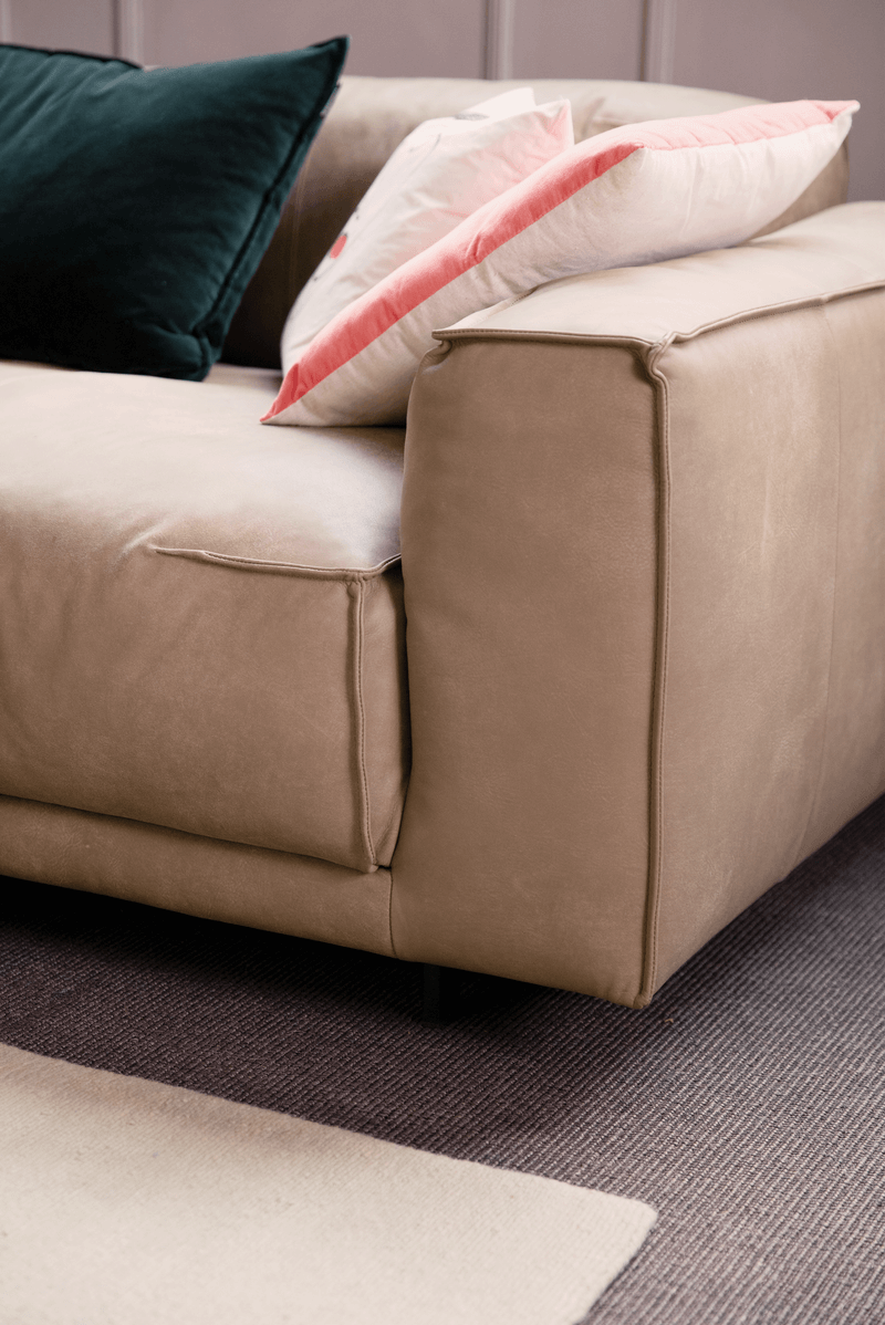 Bequemes, modernes Sofa in Beige mit dekorativen Kissen in Dunkelgrün und Rosa