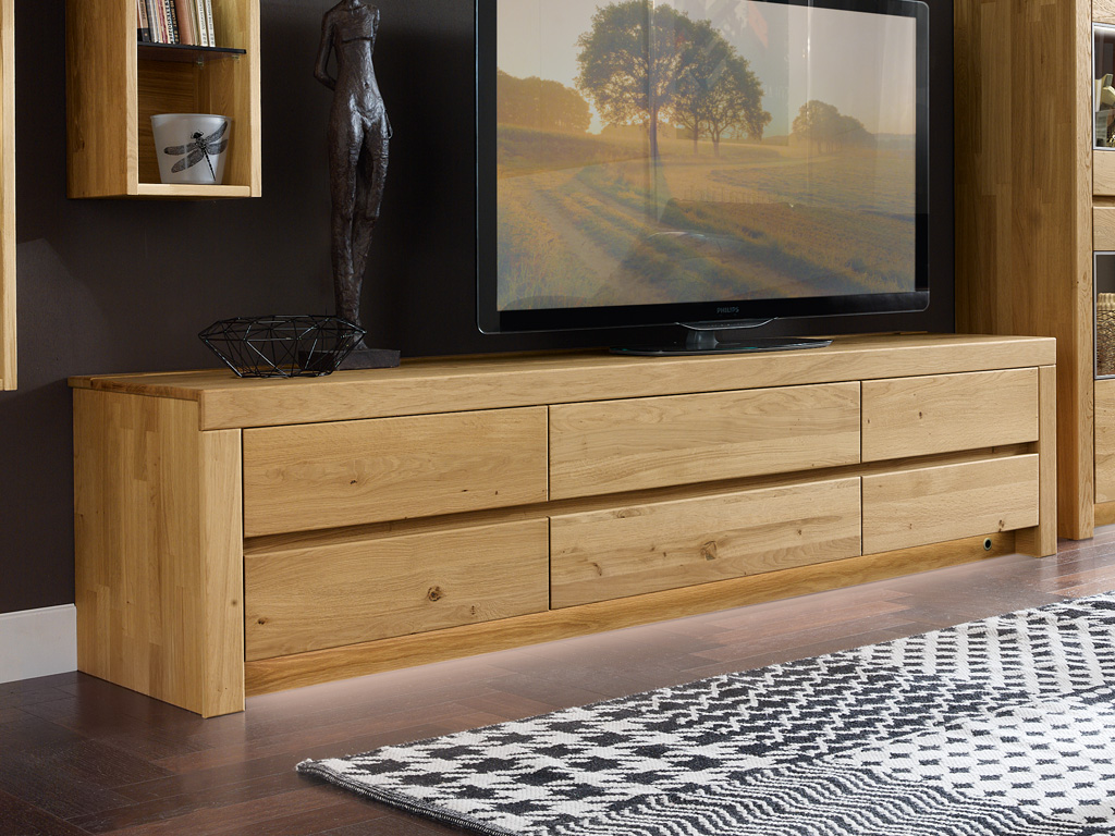 Wöstmann Soleo 3000 - Lowboard | Type 1155/1150 | B: 211,2 cm | konfigurierbar Moderne TV-Bank aus Eichenholz mit mehreren Schubladen in einem stilvoll eingerichteten Wohnzimmer mit Fernseher, dekorativer Skulptur und Teppich.