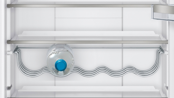 Ein Kühlschrank mit einem speziellen Flaschenhalter, in dem eine Wasserflasche liegt.