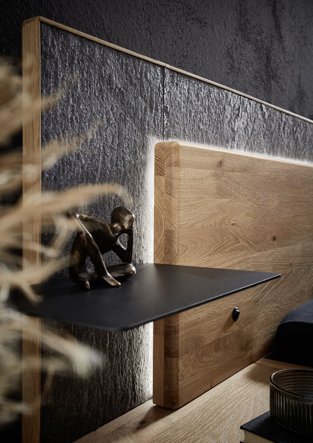 Detailaufnahme eines Bettkopfteils mit Ablage und Holzbeleuchtung sowie einer graunen Umrandung