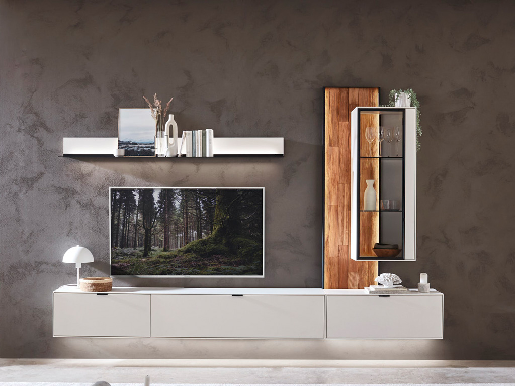 Wöstmann WM 2470 - Wohnwand  | Type 0008/0108 Stilvolles Wohnzimmer-Design mit schwebendem Sideboard, Wandregal und beleuchtetem TV-Bereich neben einer Glasvitrine auf rustikaler Wand