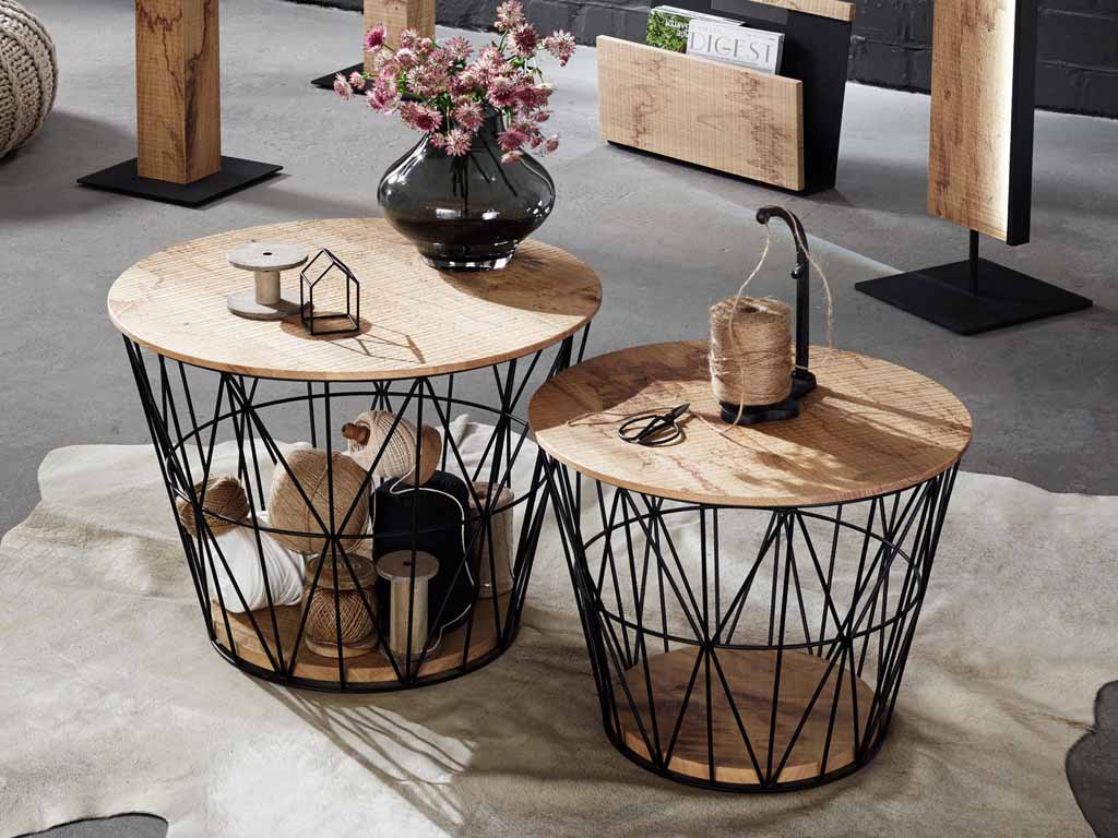 hartmann Naturstücke - Couchtisch, klein | 1071 | Riffeiche Umato Zwei Couchtische mit Holzplatten und metallischen Körben als Unterbau, dekoriert mit Blumen, Schnur und Kerzenständer, auf einem hellen Teppich.