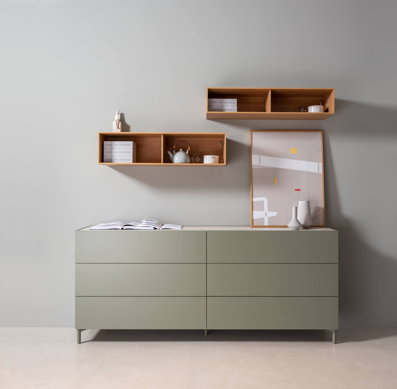 Schlichte Kommode in Grau mit hölzernen Wandregalen, Dekorationen und einem gerahmten Bild.