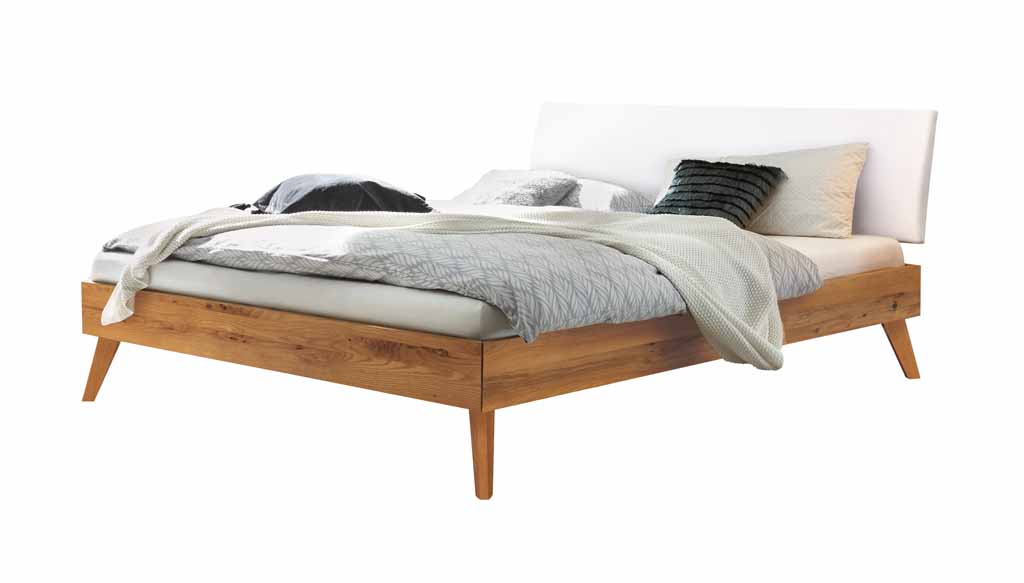 Hasena Trento - Bett Pesaro | Wildeiche natur, geölt | Kopfteil Kunstleder weiß Ein stilvolles Bett mit Holzrahmen, weißem Kopfteil und dekorativer Bettwäsche in einem Schlafzimmer