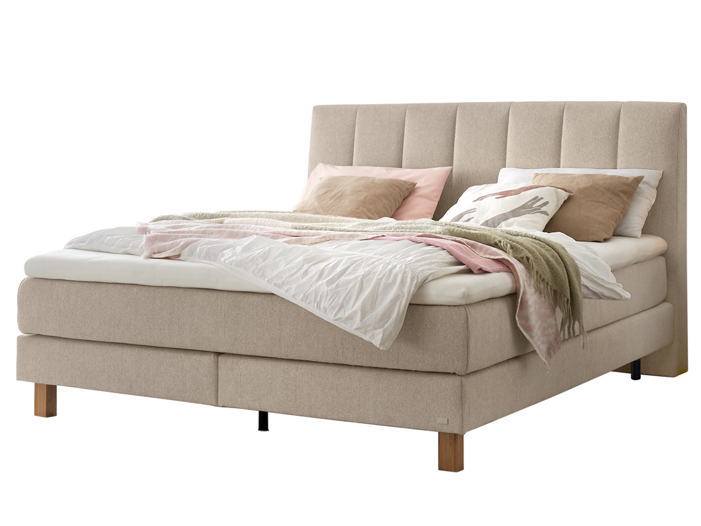 Ein Boxspringbett in hellem Beige mit einem gesteppten Kopfteil, freigestellt auf weißem Hintergrund.
