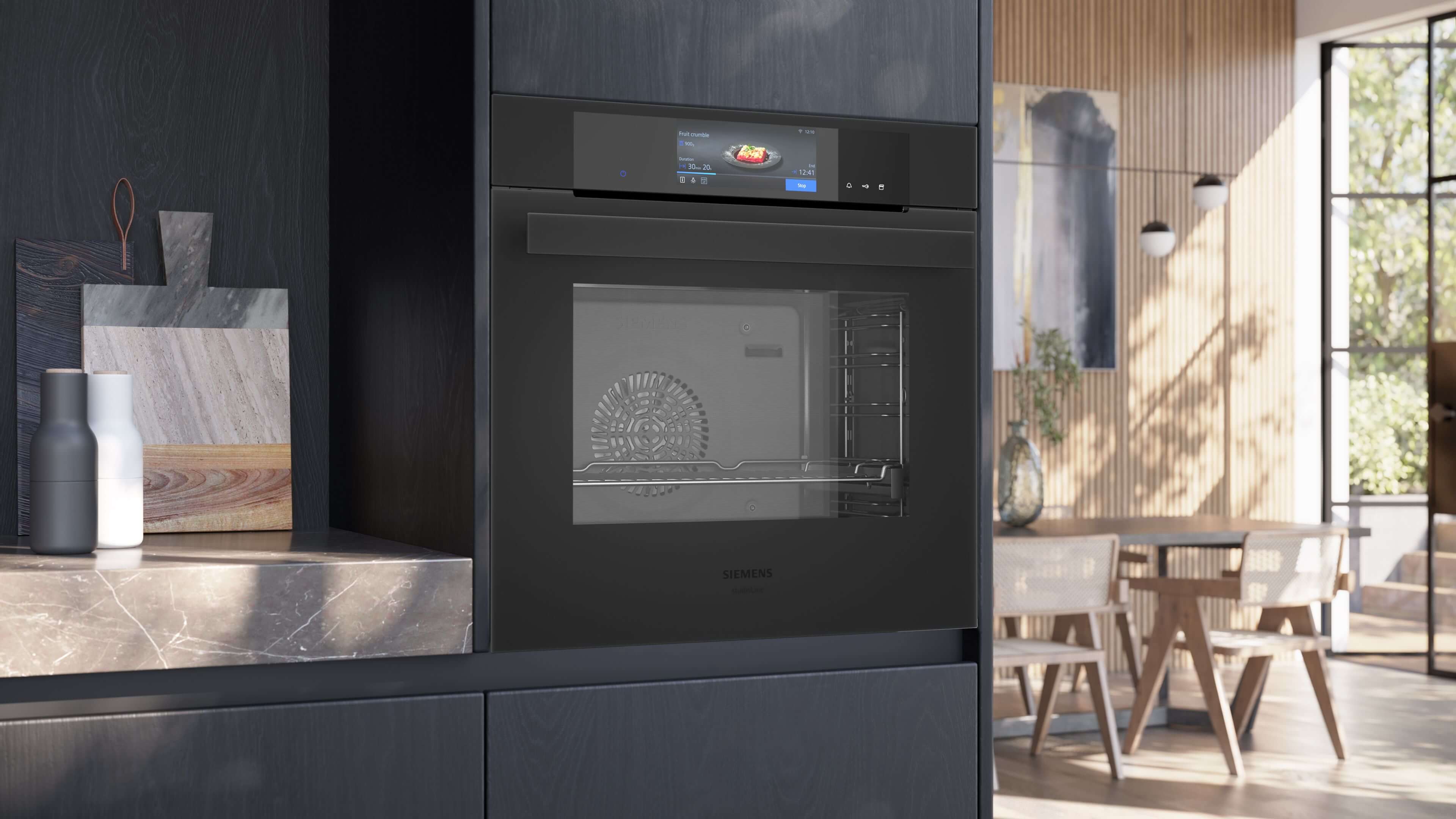 Einbau-Dampfbackofen Siemens HS938GDM1 in einer modernen, dunklen Küche. Das schwarze Glasdesign und das leuchtende Touch-Display fügen sich nahtlos in die grifflose Schrankwand ein.