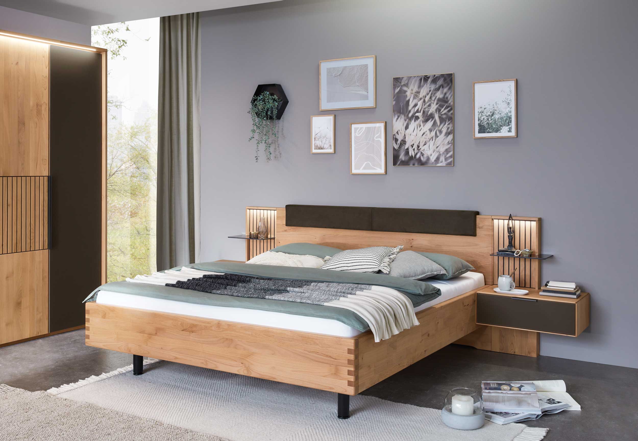 Wöstmann WSM 4400 - Bettanlage | Erle massiv | konfigurierbar Ein stilvoll eingerichtetes Schlafzimmer mit einem Holzbett, dekorativen Kissen, minimalistischer Wanddekoration und einem gemütlichen Ambiente.