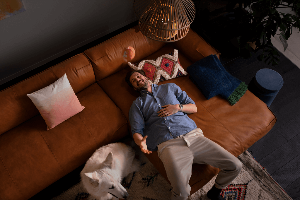 Mann mit Hund auf Sofa liegend