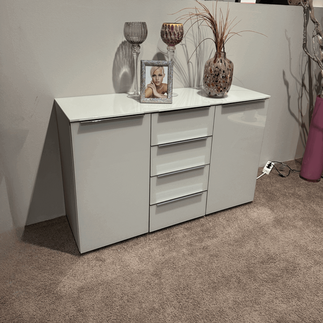 Staud SONATE | Kombikommode Weißer Schrank mit Schubladen, dekoriert mit Vasen, Kerzenhaltern und einem gerahmten Foto auf einem Teppichboden