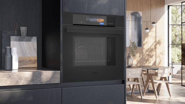 Moderne, schwarze Einbauküche mit dem Siemens iQ700 Backofen in der Frontansicht. Das hochauflösende TFT-Full-Touchdisplay zeigt ein aktives Menü mit Speisenbildern.
