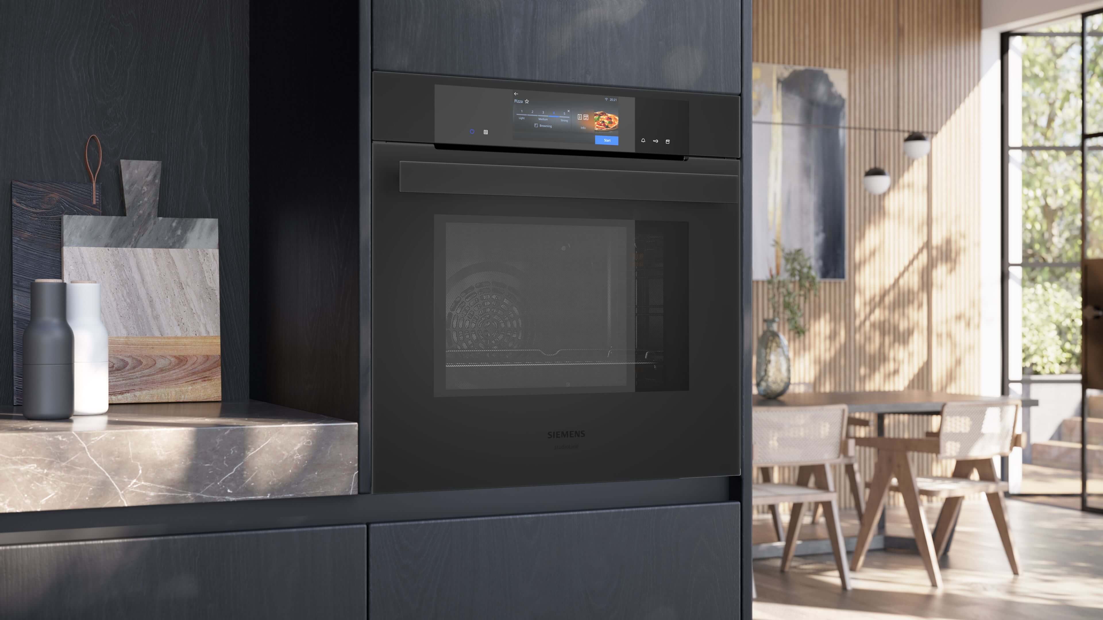 Moderne, schwarze Einbauküche mit dem Siemens iQ700 Backofen in der Frontansicht. Das hochauflösende TFT-Full-Touchdisplay zeigt ein aktives Menü mit Speisenbildern.