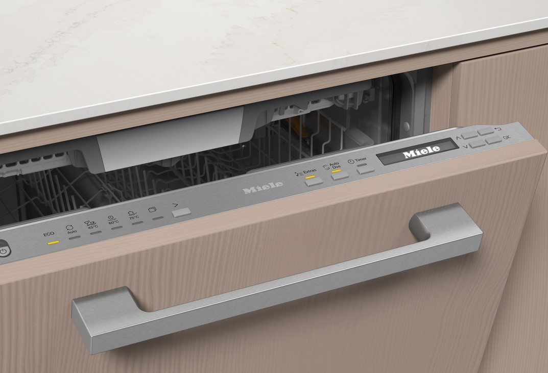    Eine Nahaufnahme des Bedienfelds eines Miele G 7191 SCVi AD Geschirrspülers, der in eine beige Küchenfront integriert ist. Man sieht die silberne Griffleiste und das Miele-Display mit den Tasten.