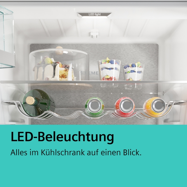 Innenansicht eines Kühlschranks mit LED-Beleuchtung, Kuchen und Getränken auf den Regalen