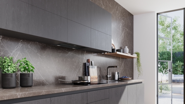 Gesamtansicht einer modernen Küche mit dunklen Hängeschränken und Unterschränken, einer marmorierten Rückwand und Arbeitsplatte. Die schwarze Dunstabzugshaube ist unauffällig in die Oberschränke integriert. Im Hintergrund ist eine Glastür zu sehen.