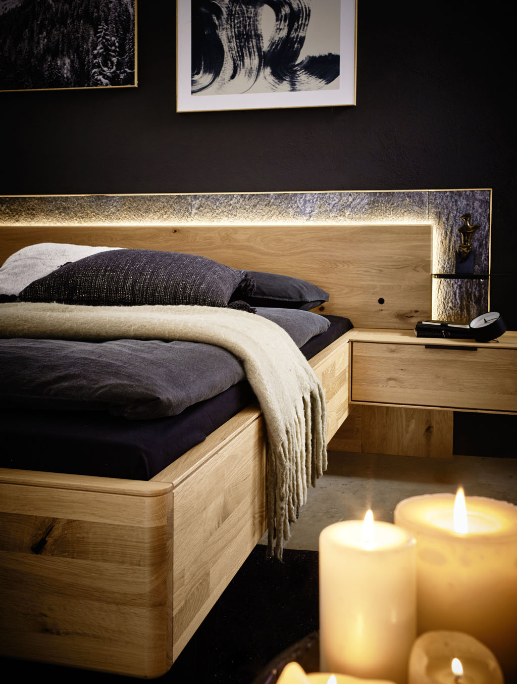 Ambienteaufnahme mit Kerzen mit einem Holzbett im Hintergrund stilvolld dekoriert