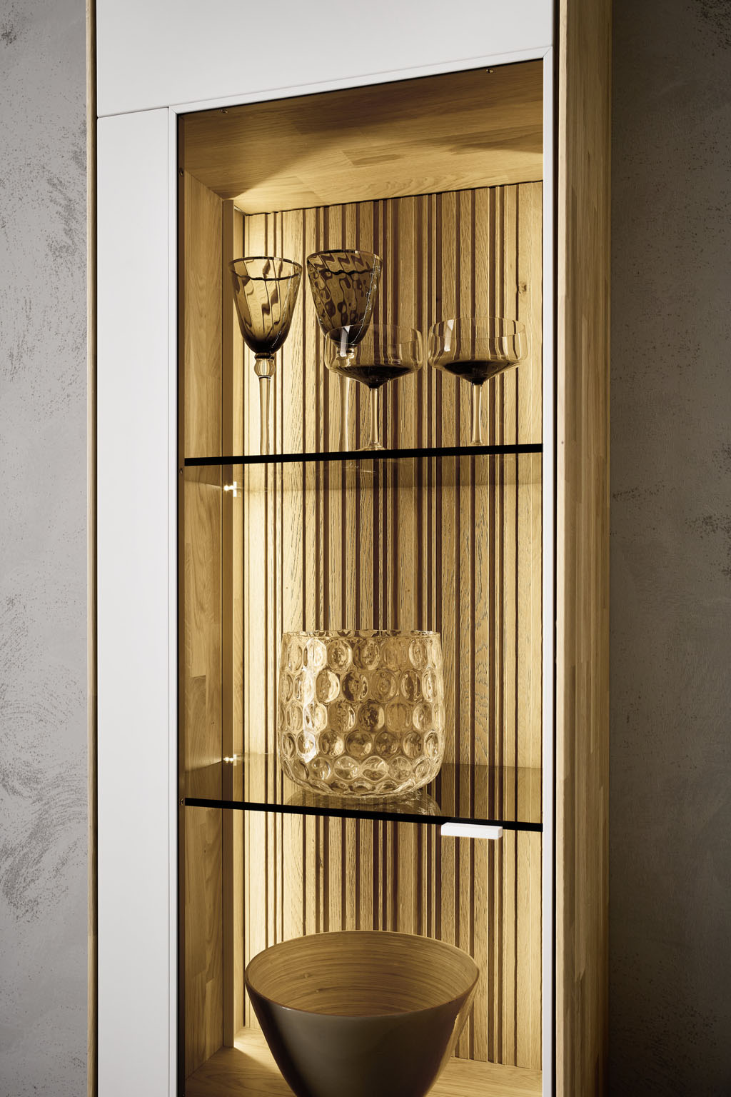 Detailaufnahme eines braun-weißen Vitrinenschrankes mit Beleuchtung stilvoll dekoriert