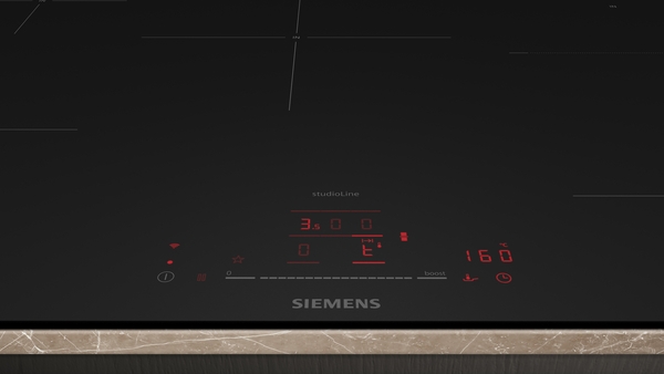 Nahaufnahme des unteren Bedienfelds eines schwarzen Siemens StudioLine Induktionskochfelds. Man sieht die roten Digitalanzeigen für die Leistungsstufen und Temperaturbereiche (z.B. "160 °C") sowie die Touch-Bedienung.