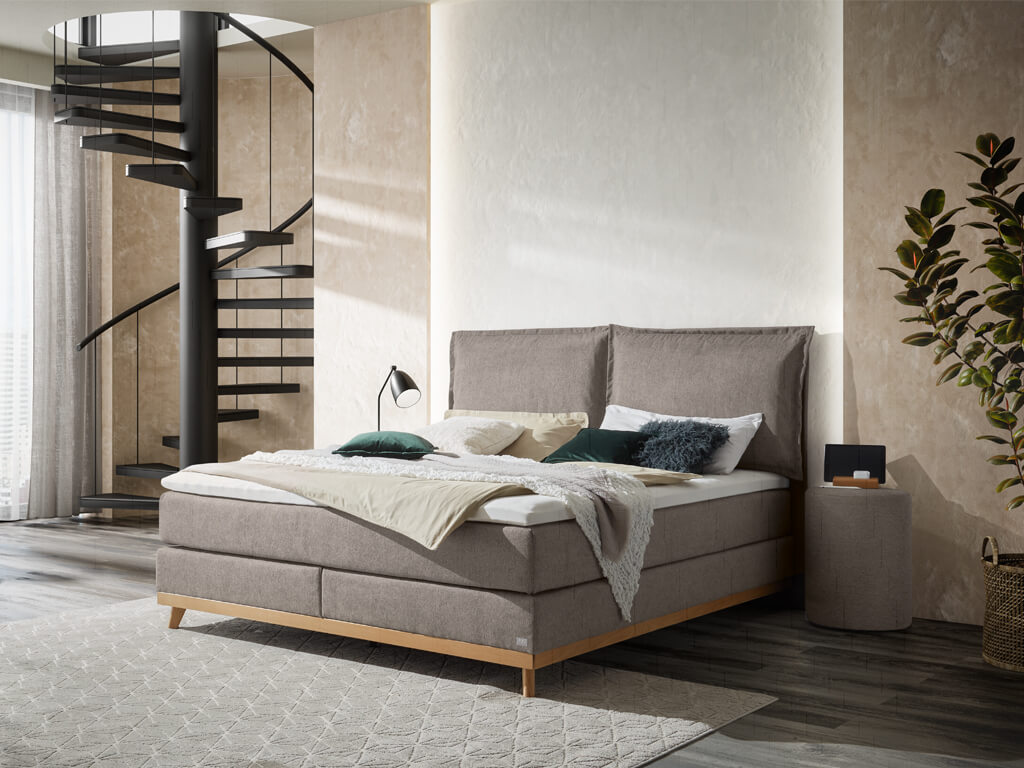 Boxspringbett Hasena Pronto Imelda in Grauton mit einem Holzfußgestell aus geölter Eiche in einem modern eingerichteten Schlafzimmer.