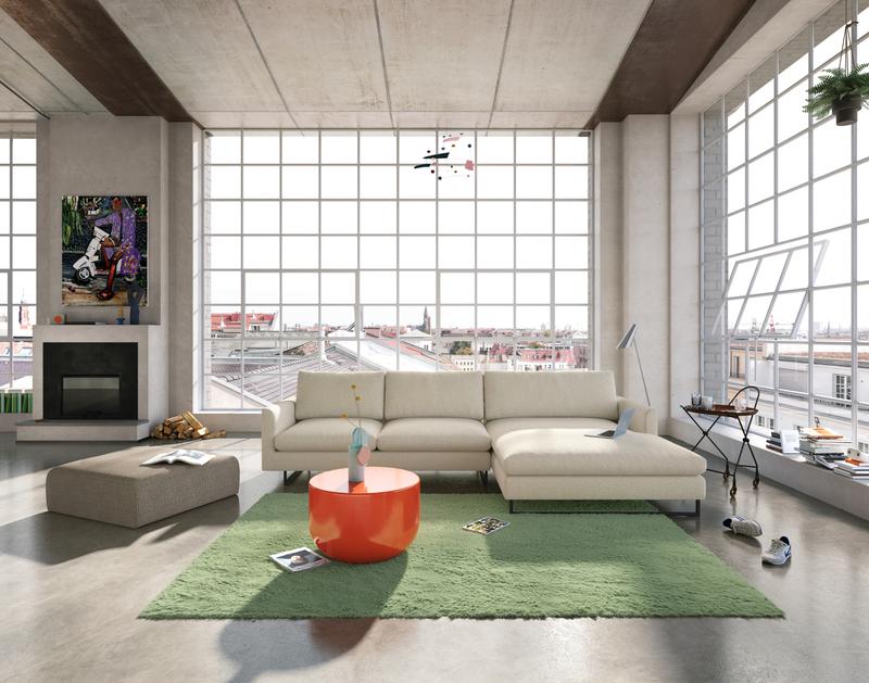 Helles Loft-Wohnzimmer mit großem weißem Sofa, grünem Teppich und orangefarbenem Couchtisch vor großen Fenstern.