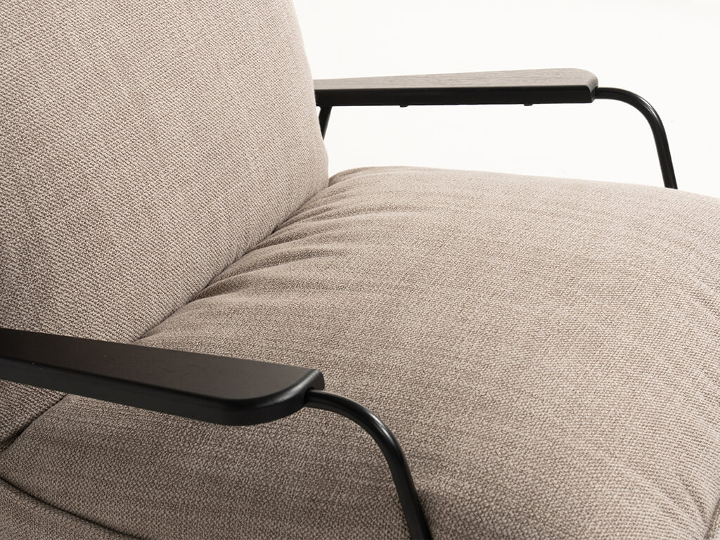 Detailaufnahme eines beigefarbenen Sofas mit schwarzen Metallarmlehnen