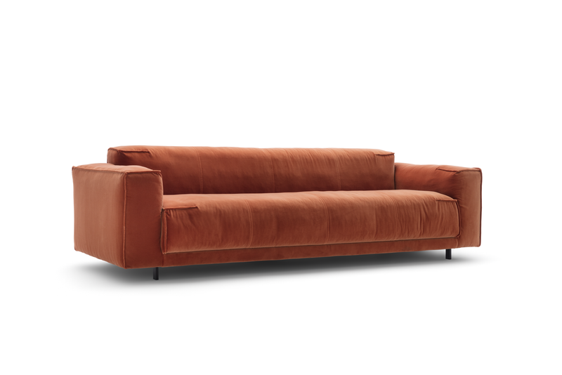 Ein modernes, rotes Sofa mit weichem Stoff und breiten Armlehnen auf hellgrauem Hintergrund