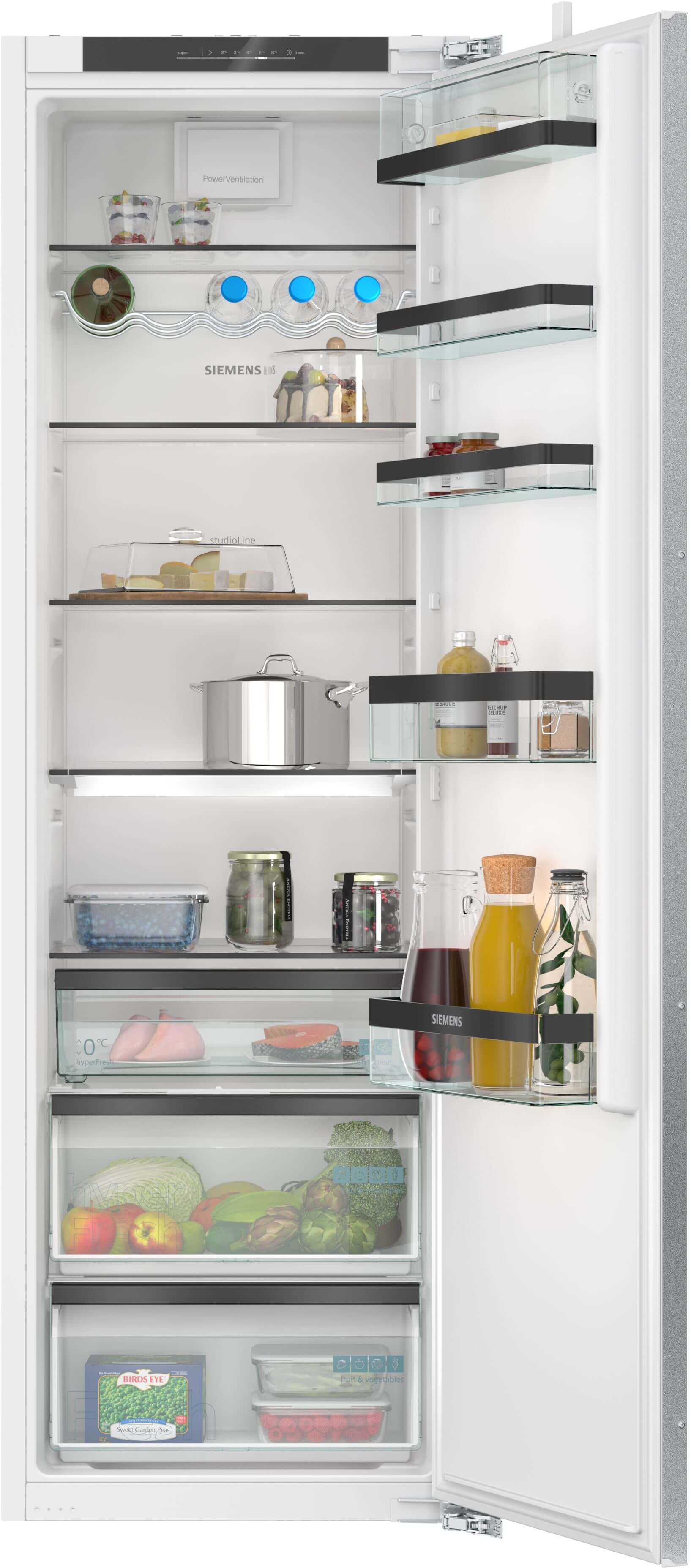 Ein offener Einbau-Kühlschrank mit Lebensmitteln wie Obst, Gemüse, Marmeladen, Getränken und Töpfen in den Regalen