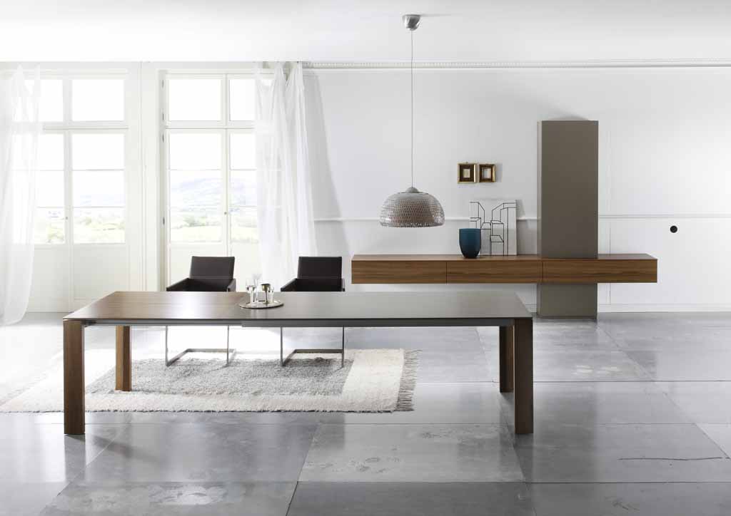 Sudbrock Cubo - Wohnwand | B: 320 cm | mit Türen und Klappen | Nussbaum natur furniert, Lack Sienna Heller Essbereich mit großem Holztisch, zwei schwarzen Stühlen, einer Hängeleuchte und schlichter Dekoration