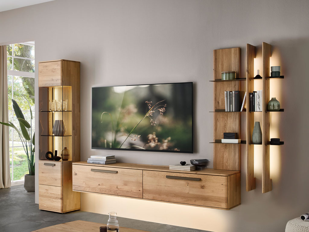 moderne Wohnwand aus Eiche mit einem beleuchtetem Hängelowboard, Aufsatzregal und Standvitrine stilvoll dekoriert in einem modernem Zimmer