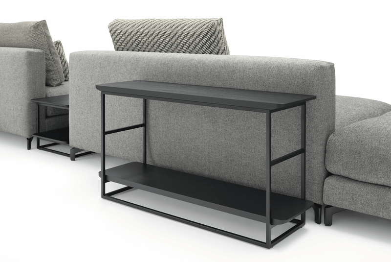 Schwarzer Metall-Konsolentisch hinter einem grauen Sofa mit Zierkissen