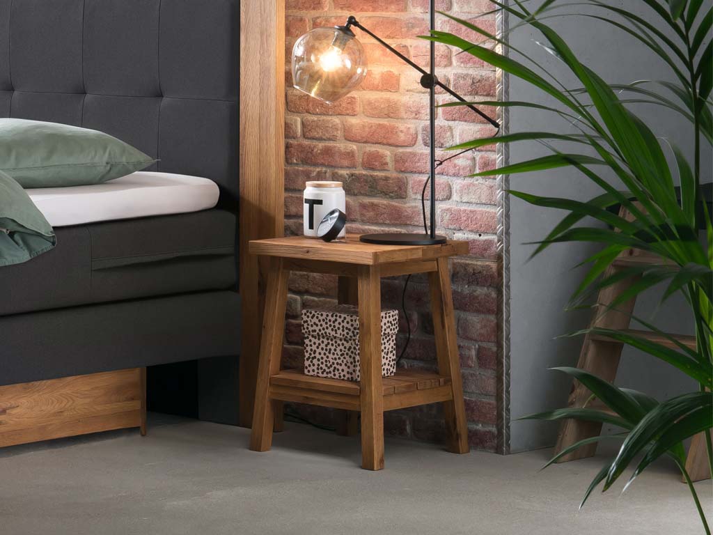 brauner Holzhocker auf vier beinen mit Ablage unten und Griffauffräsung oben auf der Platte stilvoll dekoriert in einem freundlichen zimmer ludo von hasena