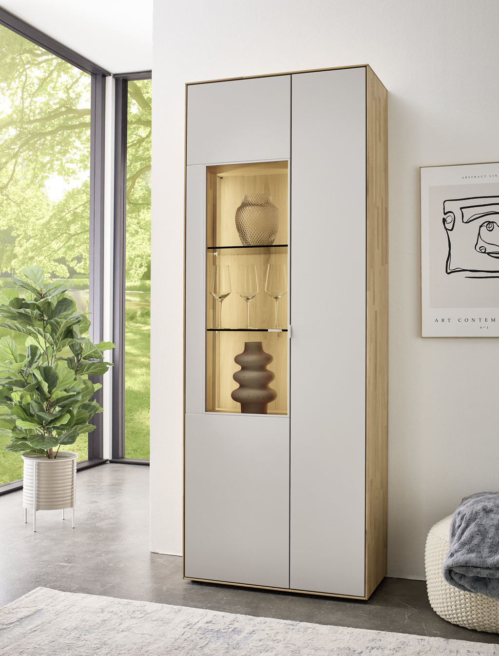 moderner Vitrinenschrank in braun-weiß mit zwei Türen und dreiteiligem Vitrinenausschnitt und Beleuchtung stilvoll dekoriert in einem modernen, hellen Raum