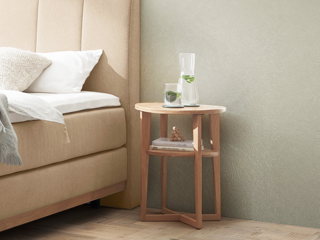  brauner runder Holznachttisch mit rundem Einlegeboden eingefasst in ein Gestell stilvoll dekoriert an einem Bett in einem modernen Zimmer Wilson von Hasena