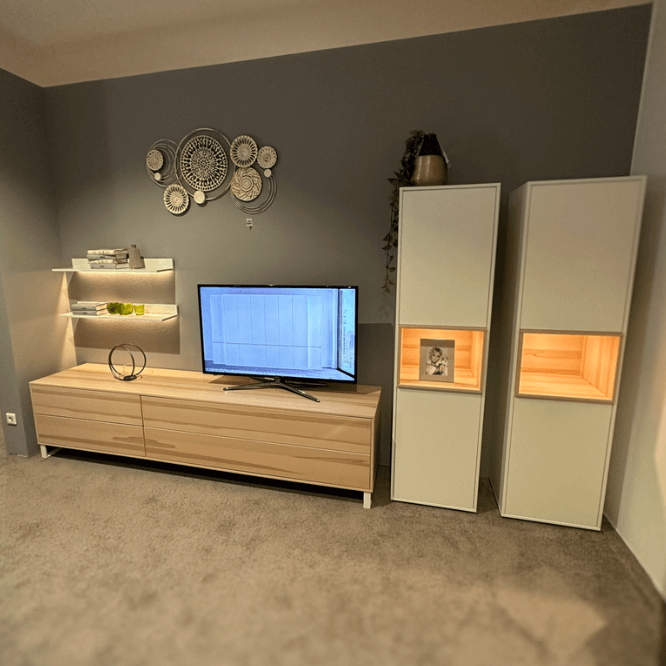 Wohnzimmer mit modernem Möbel-Set, bestehend aus einem TV-Schrank, Regalen und beleuchteten Schränken, dekoriert mit Wandkunst.