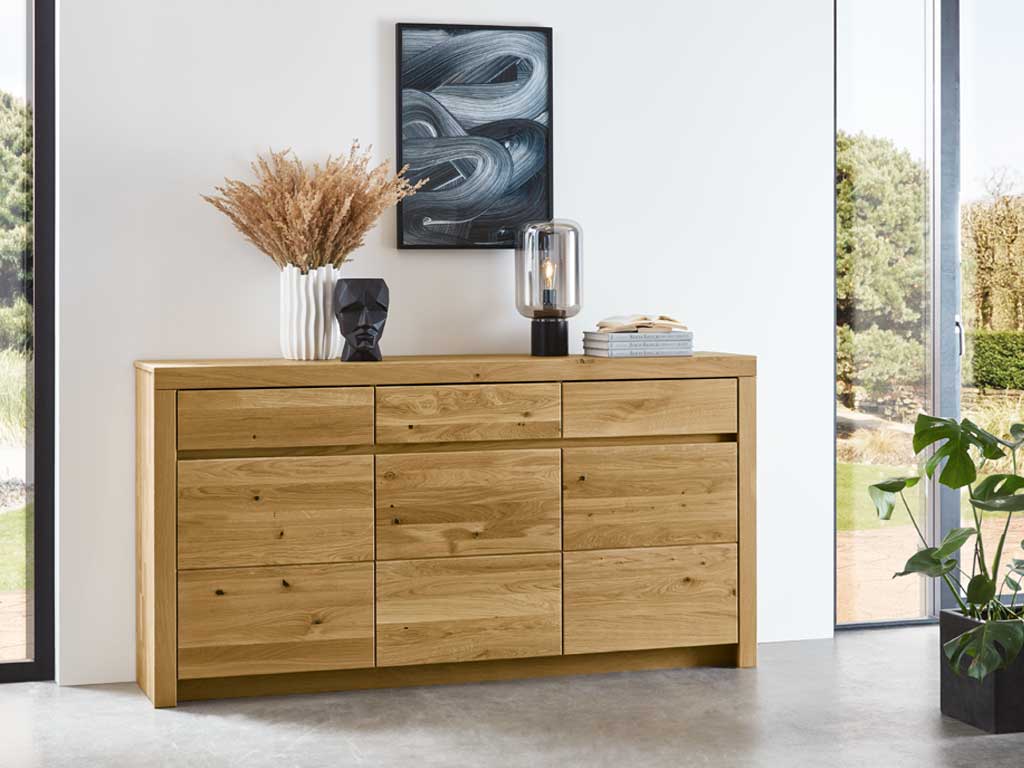 Wöstmann Soleo 3000 - Sideboard | Type 2950 | B: 190,1 cm | konfigurierbar Holzkommode mit Dekorationen in einem modernen Raum mit großen Fenstern und Pflanzen