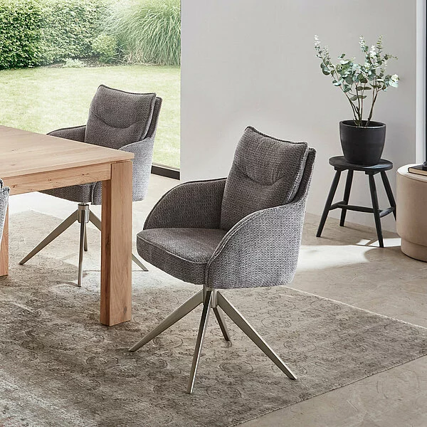 zwei graue stühle mit silberfarbigem gestell auf grau gemustertem teppich an einem holzesstisch