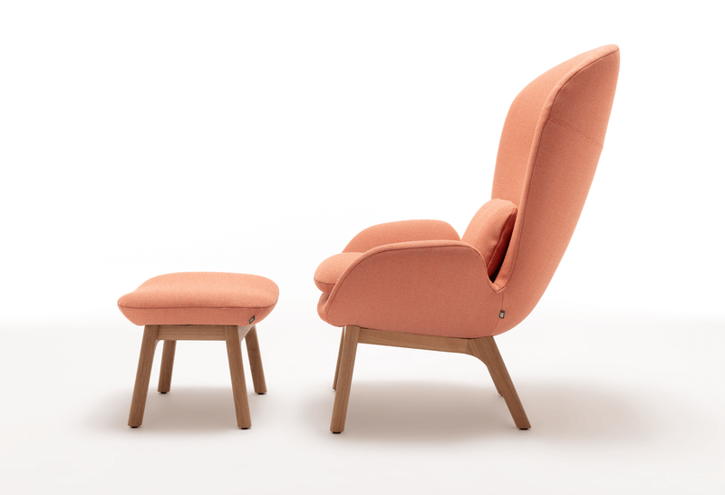 Bequemer orangefarbener Sessel mit passendem Hocker, auf Holzbeinen stehend, seitliche Ansicht